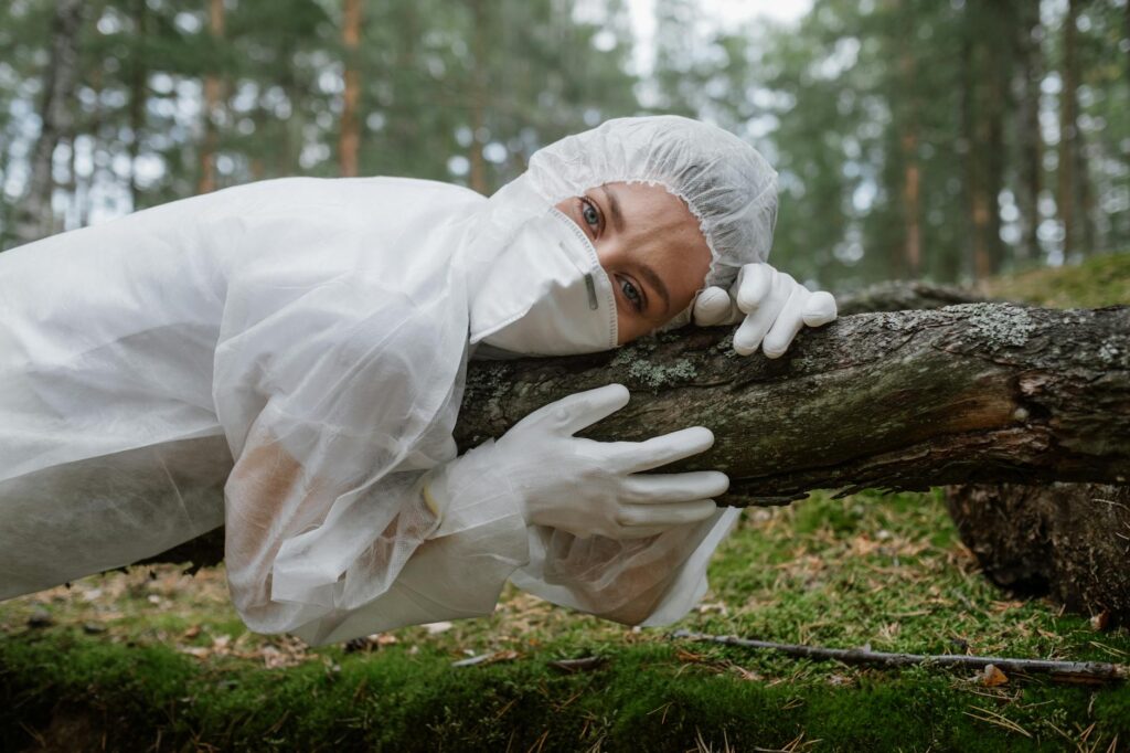 A researcher examining tree leaves in a forested setting.
