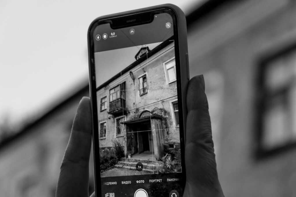 Homeowner using a smartphone to photograph a dead tree limb from the backyard for documentation purposes