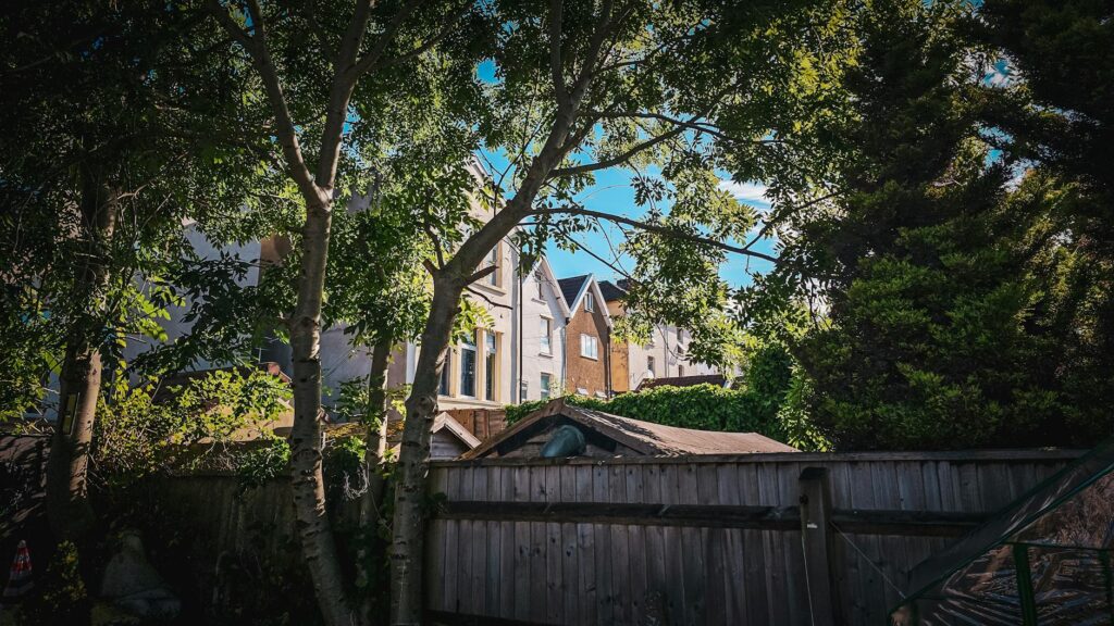Large dead tree limb hanging directly over the roof of a suburban home