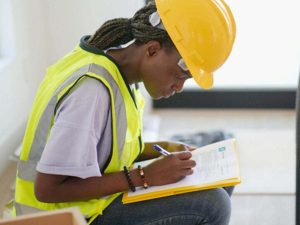 A certified arborist inspecting a tree trunk and writing assessment notes on a clipboard