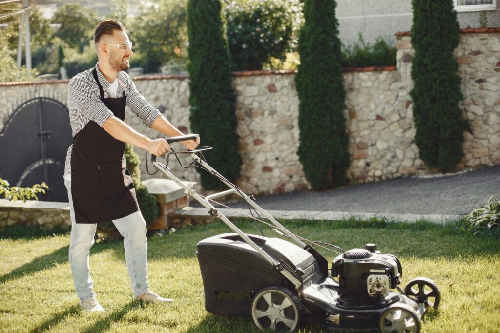 Homeowner working in a backyard garden near large trees in summer