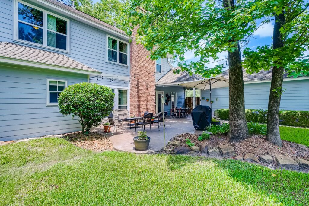A massive old shade tree providing deep canopy cover over a residential backyard in summer