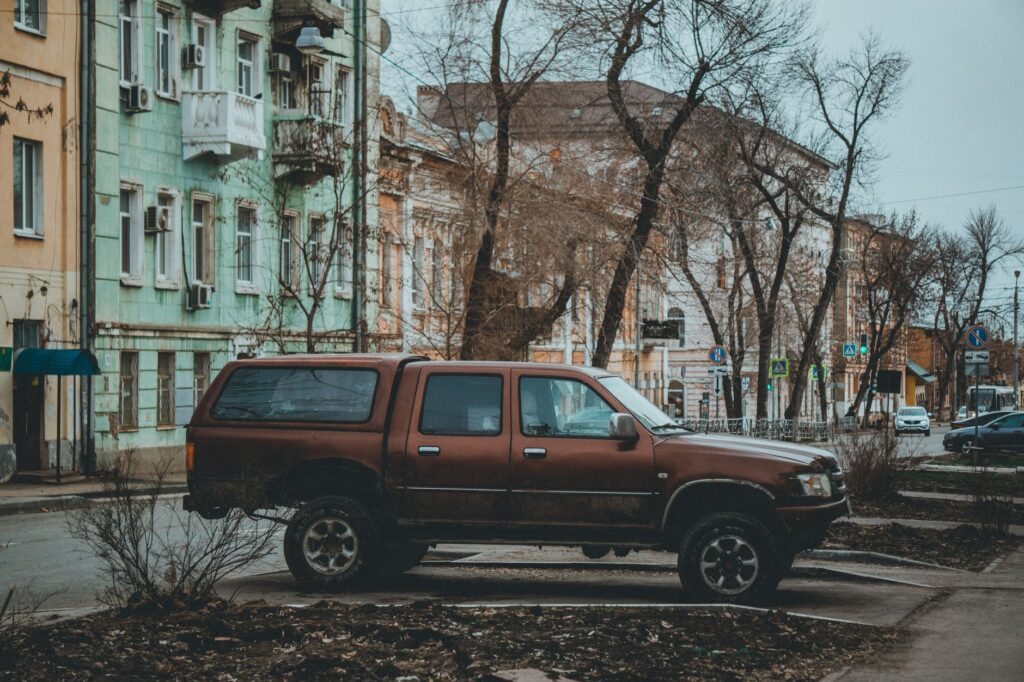 A work truck parked near a storm-damaged tree limb on a residential street