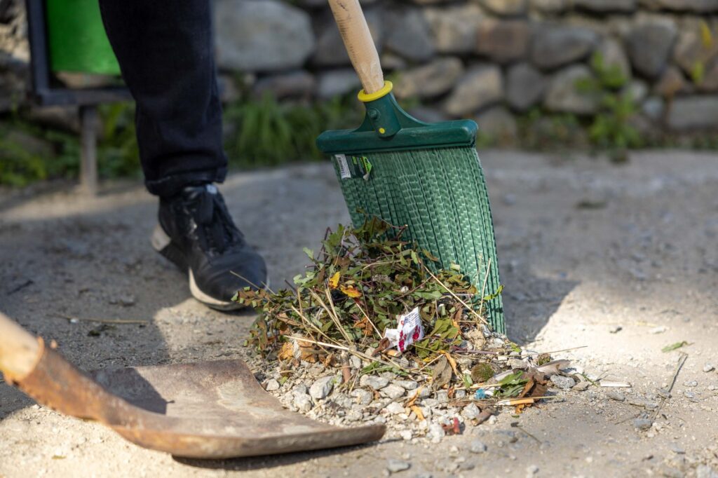 A homeowner sweeping fallen acorns off a driveway near a Middletown home