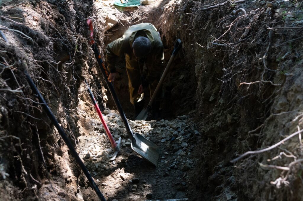 An arborist using an air spade tool to safely excavate soil from around tree roots
