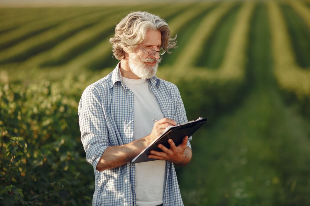An arborist recording detailed field notes on a clipboard while inspecting a tree