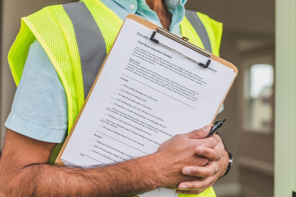 A homeowner reviewing a checklist near a storm-damaged tree in the driveway