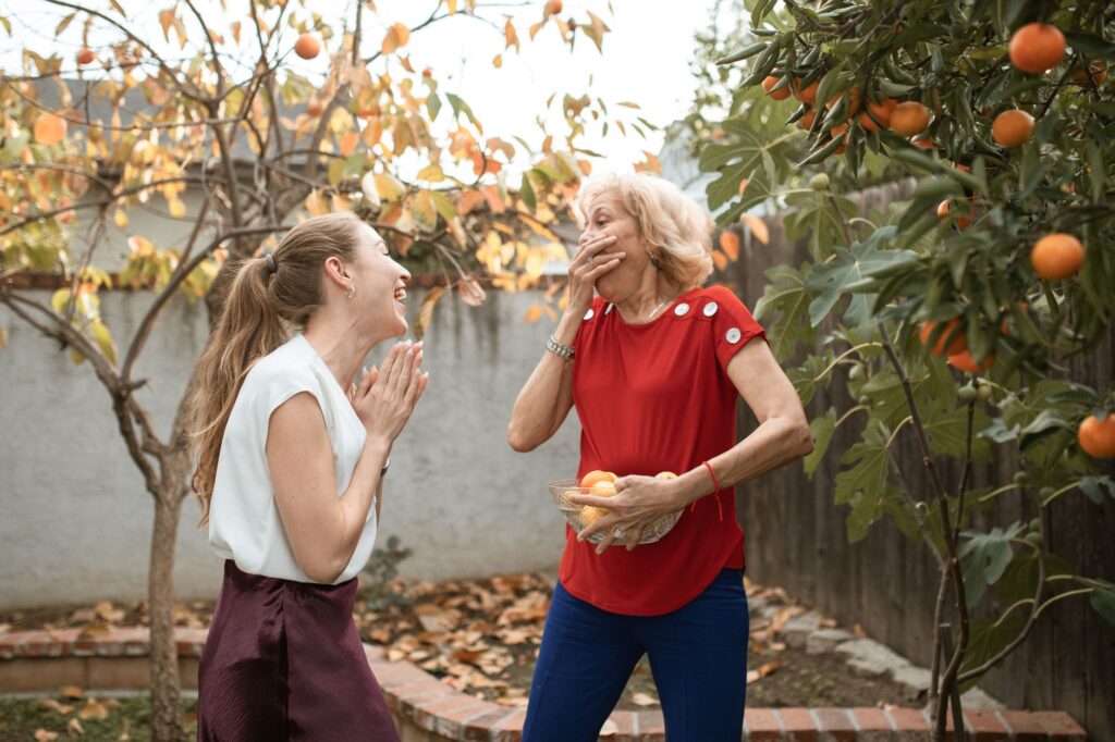 Two neighbors having a friendly conversation in a backyard near a large tree