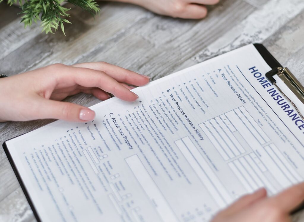 A homeowner reviewing homeowners insurance policy paperwork at a kitchen table