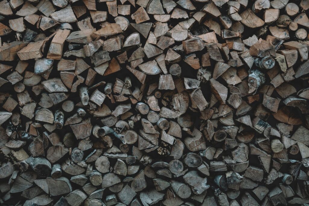A neatly stacked, top-covered firewood pile away from a house