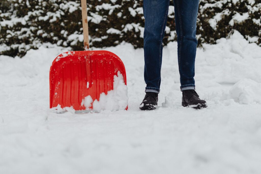 Person shoveling snow from a driveway before applying salt