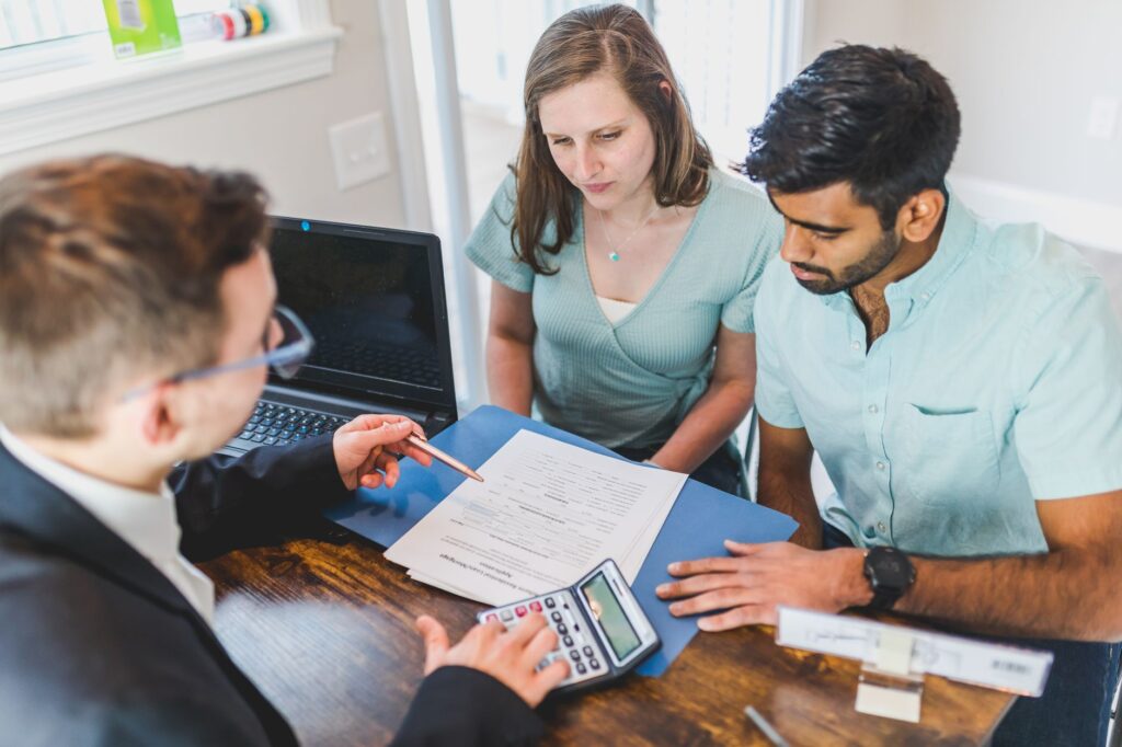 Home buyers reviewing documents in a front yard with large trees